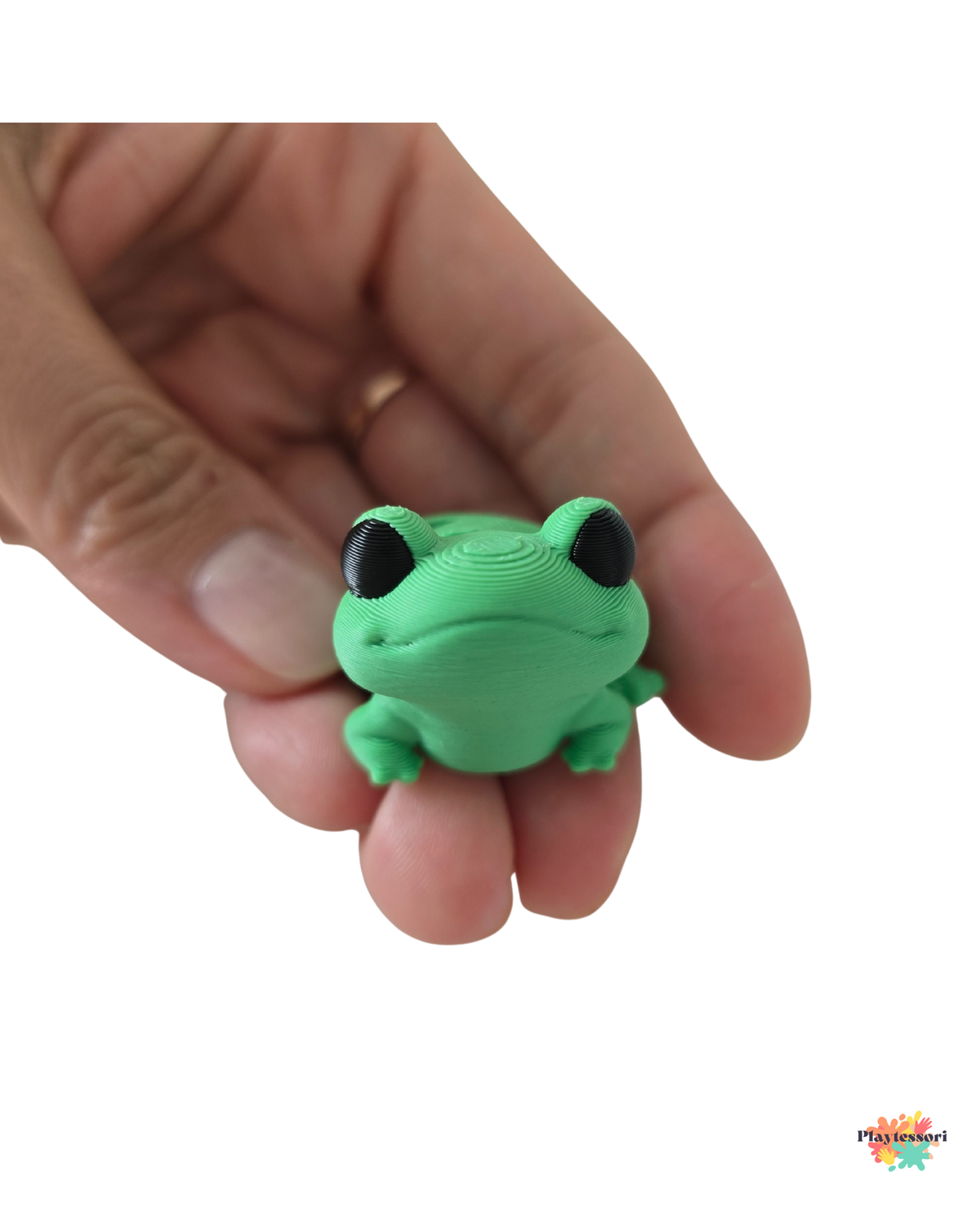 Green frog-shaped object held in a hand against a white background
