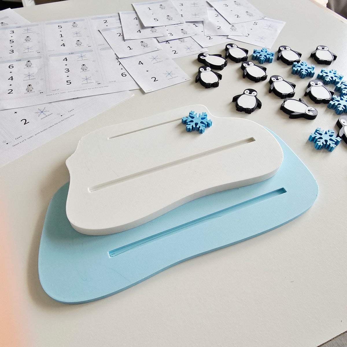 White and light blue ice floe tray, penguin and snowflake counters, printed task cards