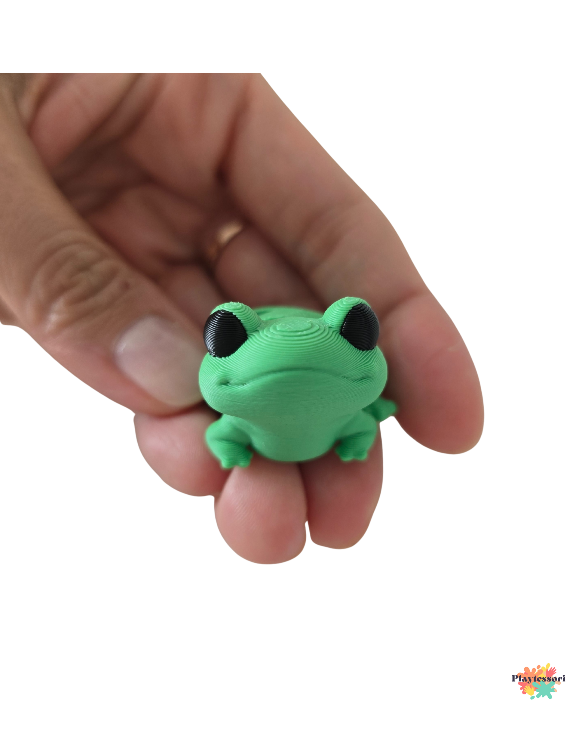 Green frog-shaped object held in a hand against a white background