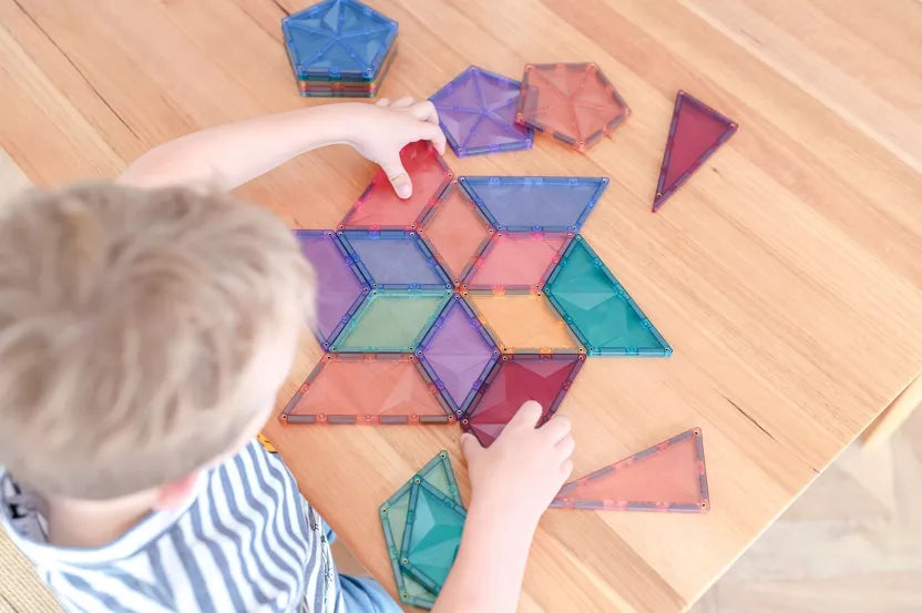 Child playing with colorful magnetic tiles on a wooden floor