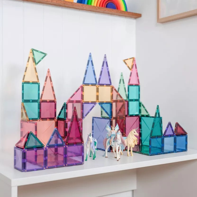 Colorful magnetic building blocks on a white surface with a rainbow toy in the background.