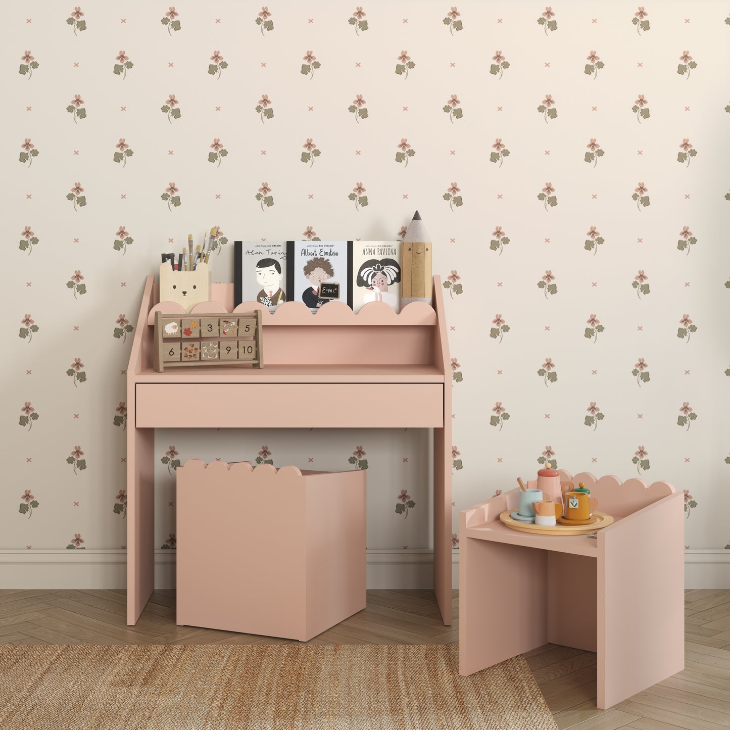 Pink desk with accessories against a floral wallpapered wall