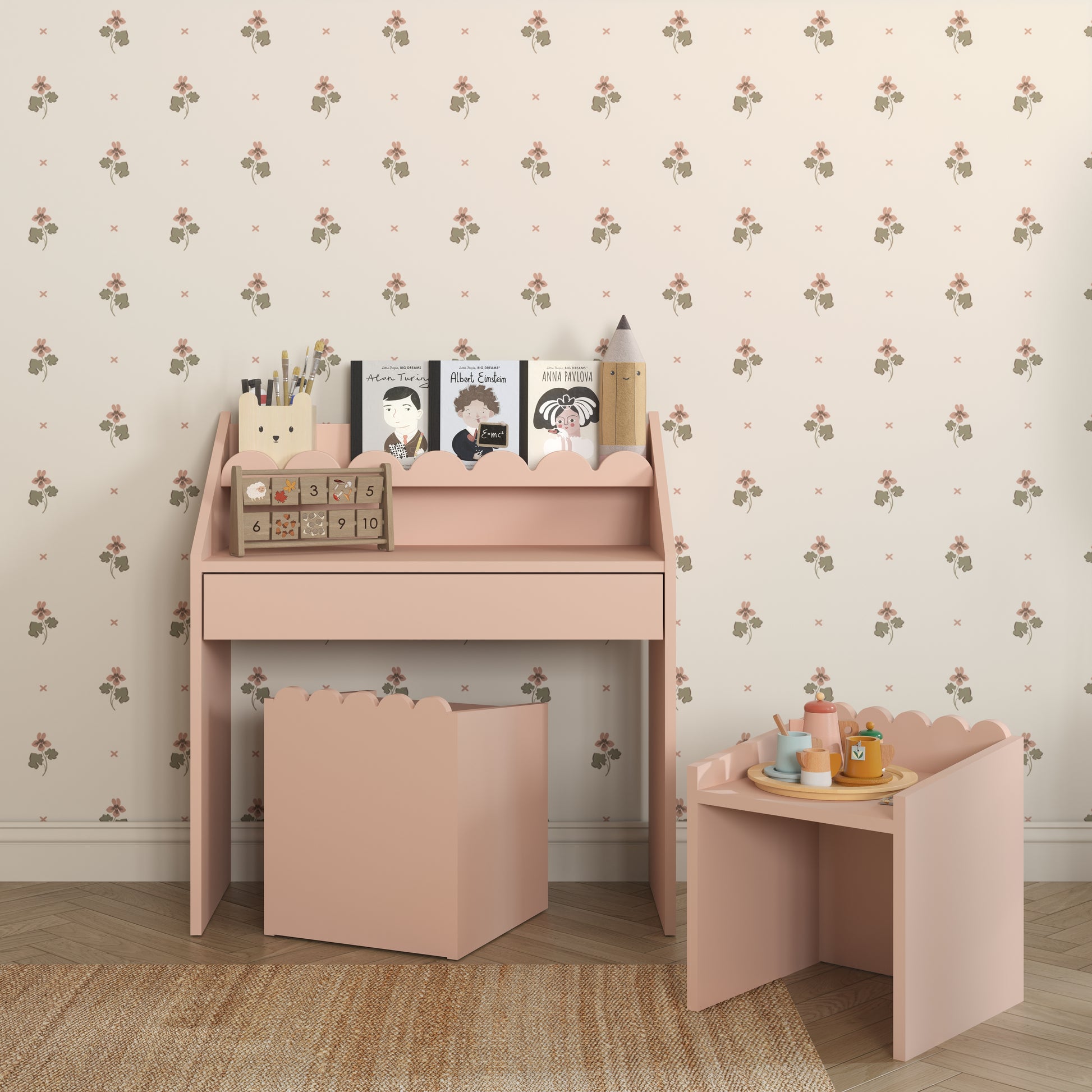 Pink desk with accessories against a floral wallpapered wall