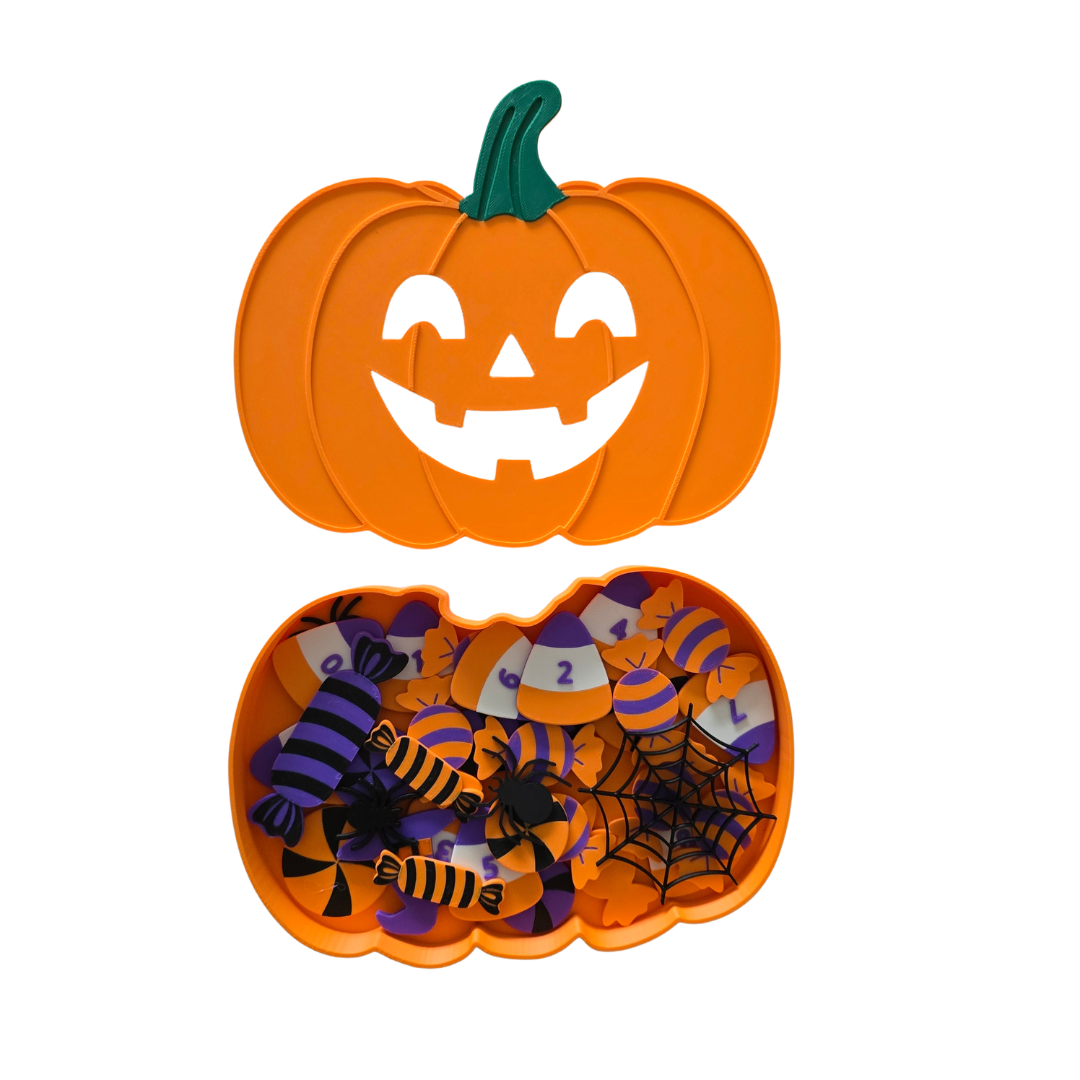 An orange pumpkin-shaped Halloween candy container with a carved jack-o'-lantern lid and an open bottom section filled with assorted candy, spiderwebs, and purple-and-orange themed pieces on a white background.
