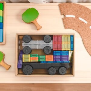 Colorful toy truck made of interlocking blocks on a wooden surface with a cork board in the background.