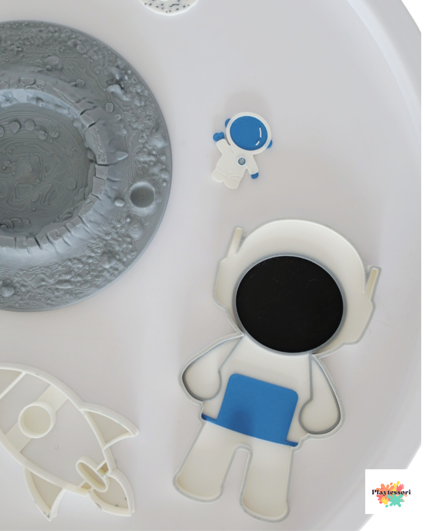 Close-up of 3D printed astronaut sensory tray and mini astronaut figure in white and blue color inside a sensory play table.