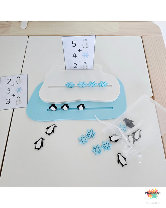 Zestaw do liczenia Arktyka z białą tacką lodową, pingwinami i niebieskimi śnieżynkami, wraz z kartami do dodawania – przygotowany na stole do zabawy edukacyjnej.