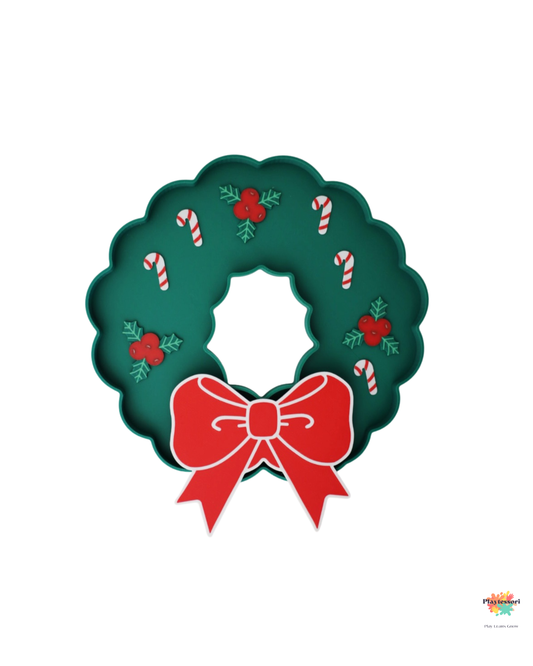 Zielona wysypywanka sensoryczna w kształcie świątecznego wianka z czerwonymi ozdobami, liskami ostrokrzewu i mini laskami cukrowymi